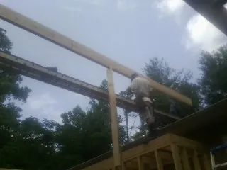 Carpenter setting a ridge beam over a new addition frame — Ice Dam Removal by Roofing Brothers in Lacombe