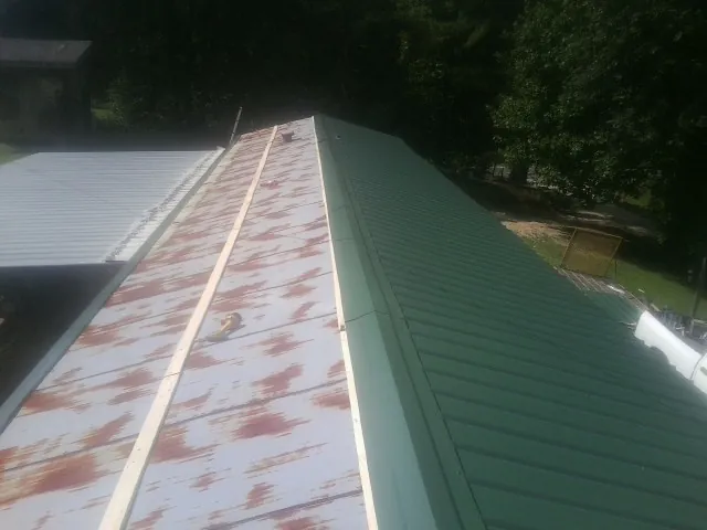 Old rusted panels beside newly installed green metal roofing — Wind Damage Roof Repair by Roofing Brothers in Lacombe