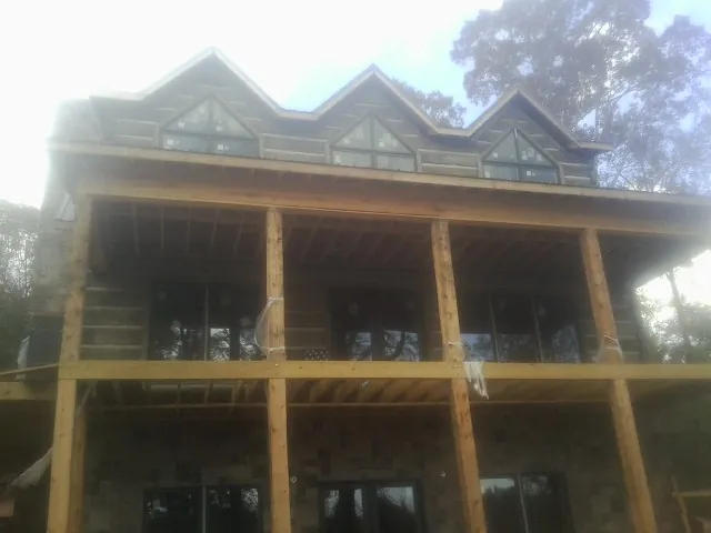 Dormers and porch framing on a large log home under construction — Roof Coating work by our crew in Lacombe