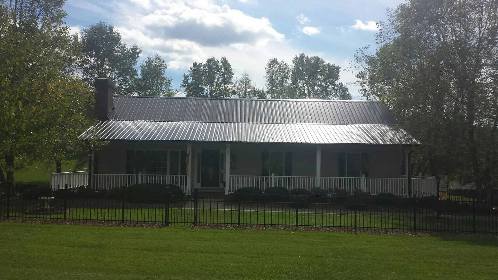 Gray metal roof on a brick ranch with a full width front porch — Gutter Guard Installation work by our crew in Lacombe